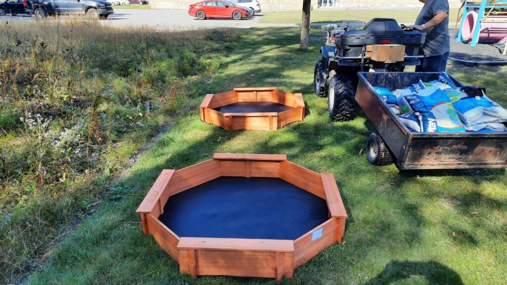 2025-09-17 - Knights of Columbus Installing Sandboxes (3) at Levack Public School. two more sandboxes empty and ready to be filled.